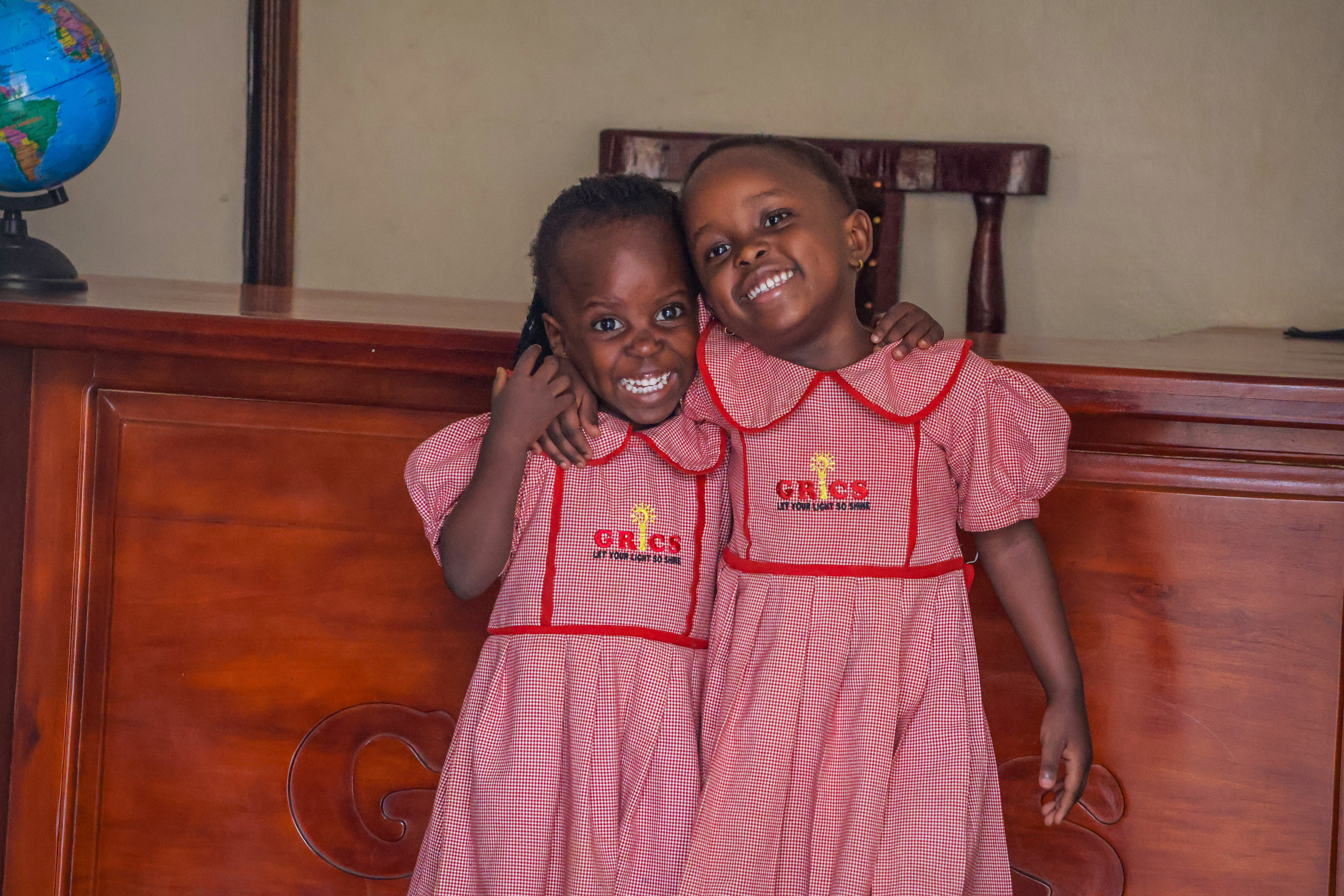 Two young GRICS learners smiling cheek to cheek in uniform